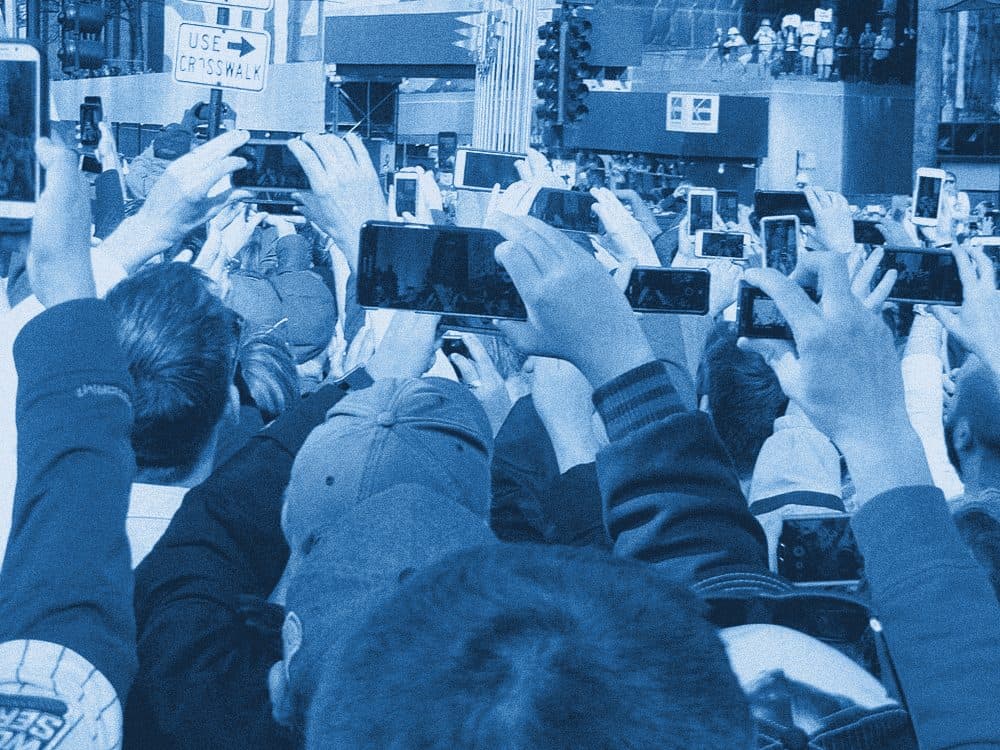 A crowd holding smartphones up above their heads, filming